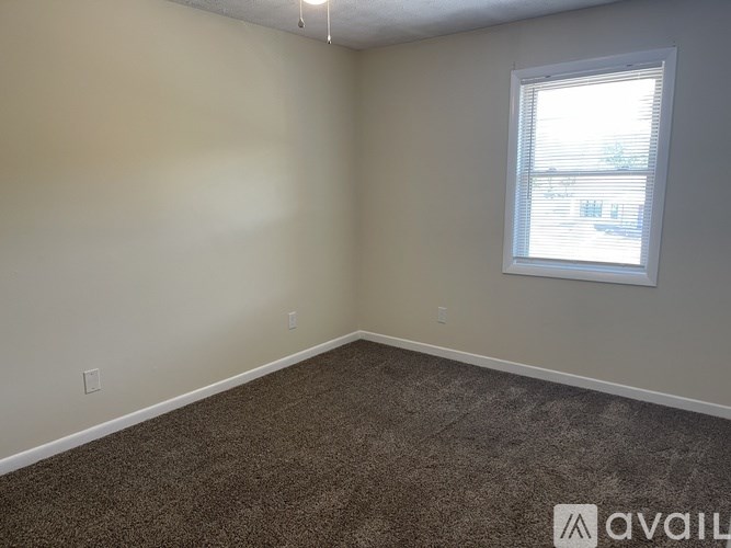 A room with a carpeted floor and a window letting in natural light.