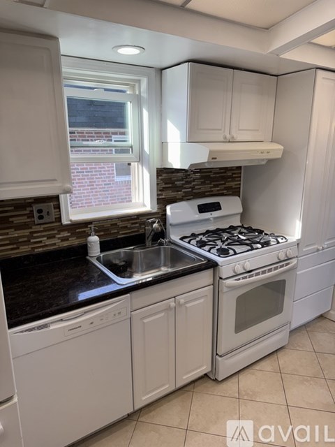 A kitchen with white cabinets and a black countertop.