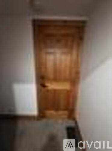 A wooden door in a room with white walls.
