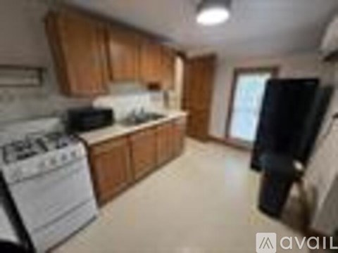 A kitchen with wooden cabinets and a black refrigerator.
