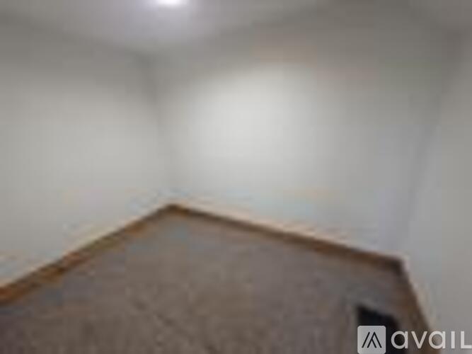A room with a brown carpet and a white wall.