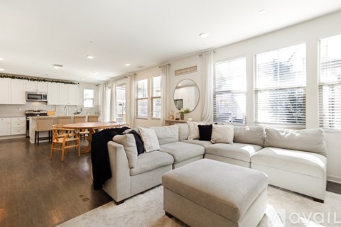 A modern living room with a white couch and a wooden dining table.