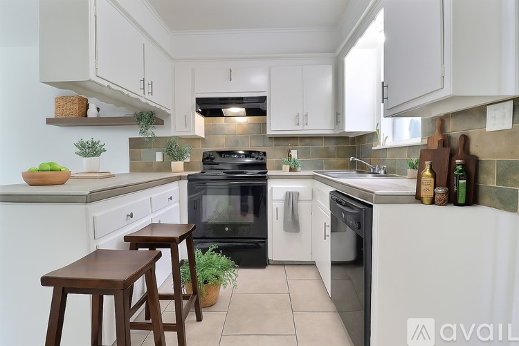 A kitchen with white cabinets and a black refrigerator.