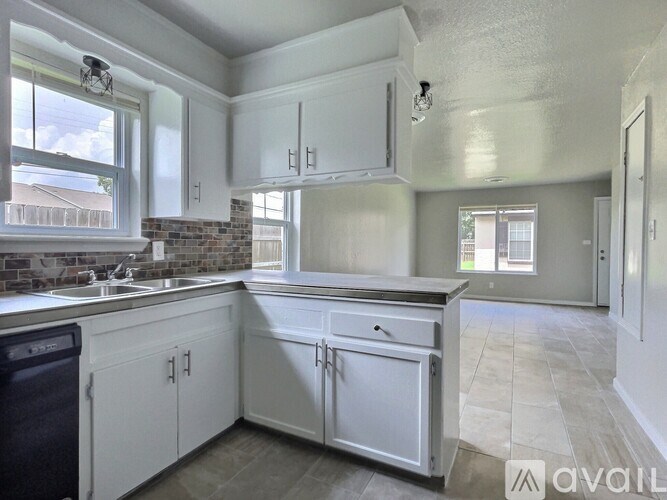 A kitchen with white cabinets and a brick backsplash is on the market.