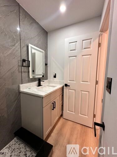 A bathroom with a sink, mirror, and wooden floors.
