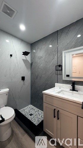 A bathroom with a toilet, sink, and shower area.