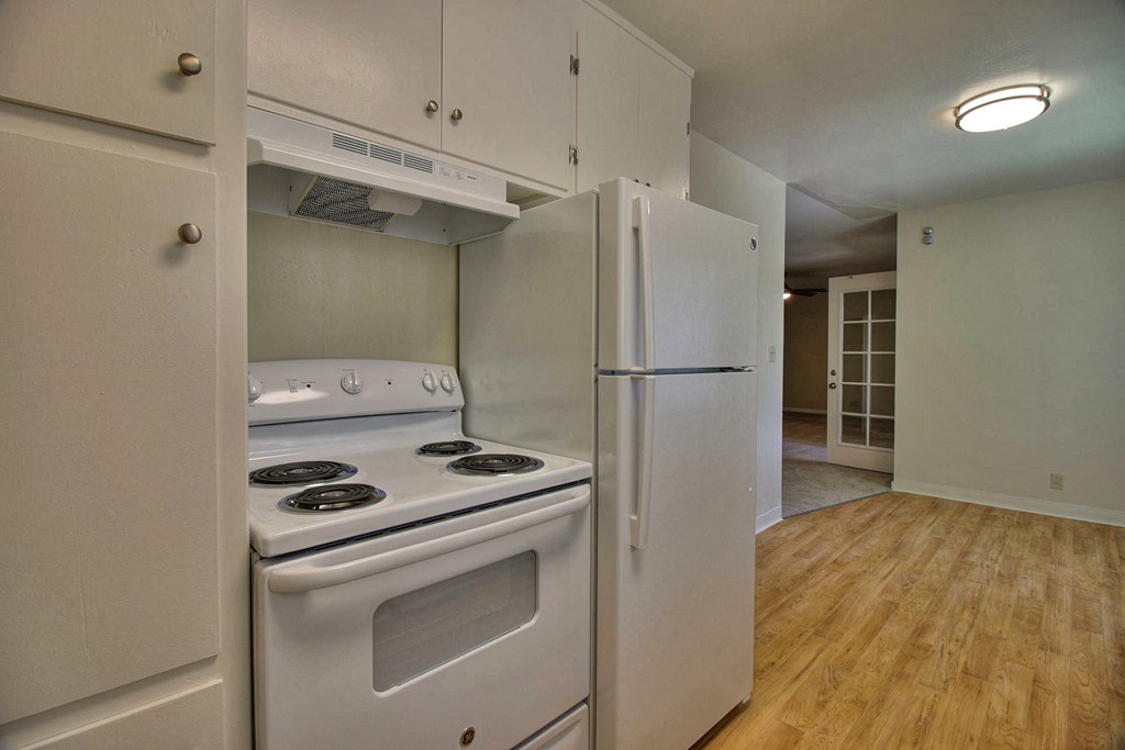 an empty kitchen with white appliances and a refrigerator