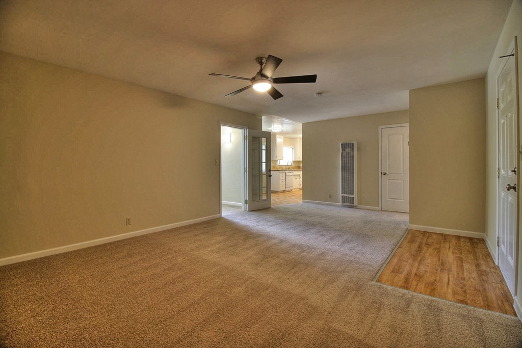an empty living room with a ceiling fan