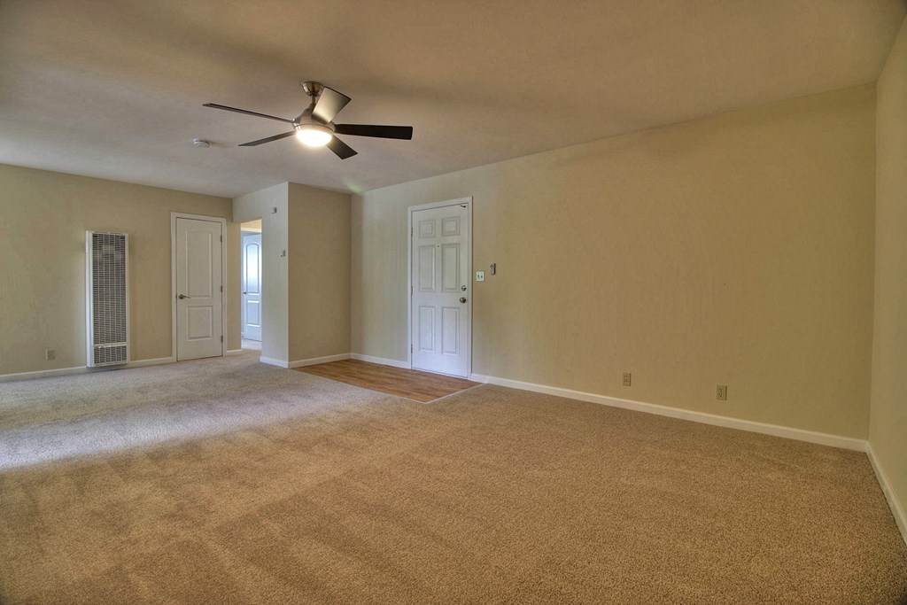 an empty living room with a ceiling fan