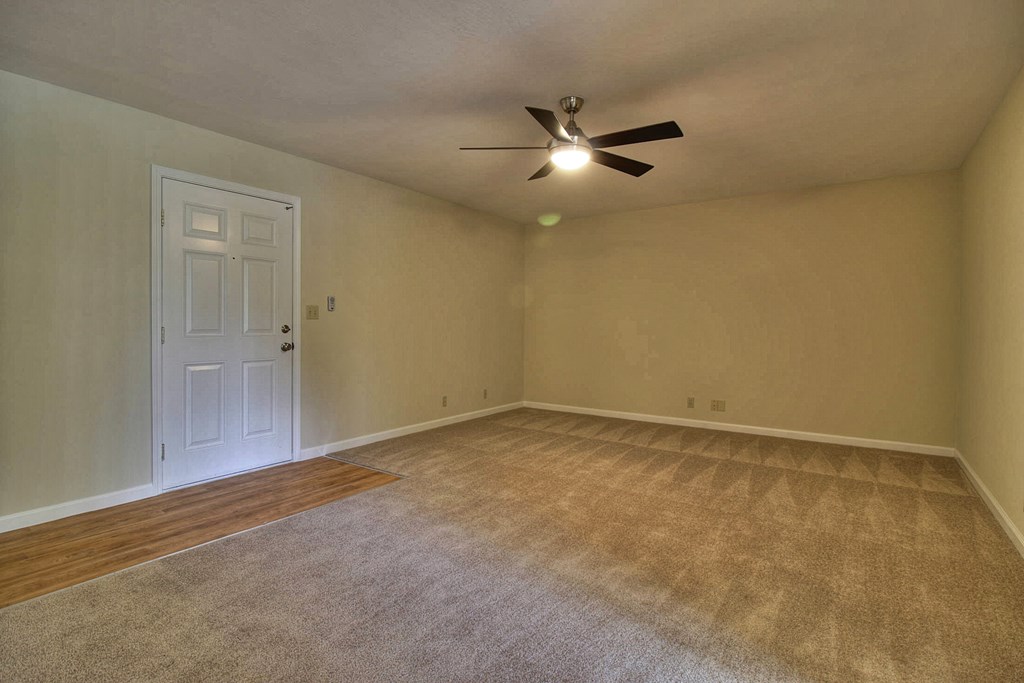 an empty living room with a ceiling fan