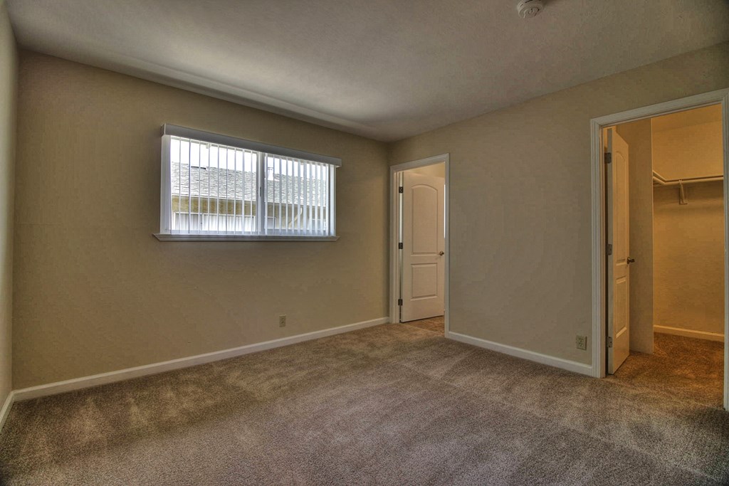 an empty living room with a window and a door to a closet