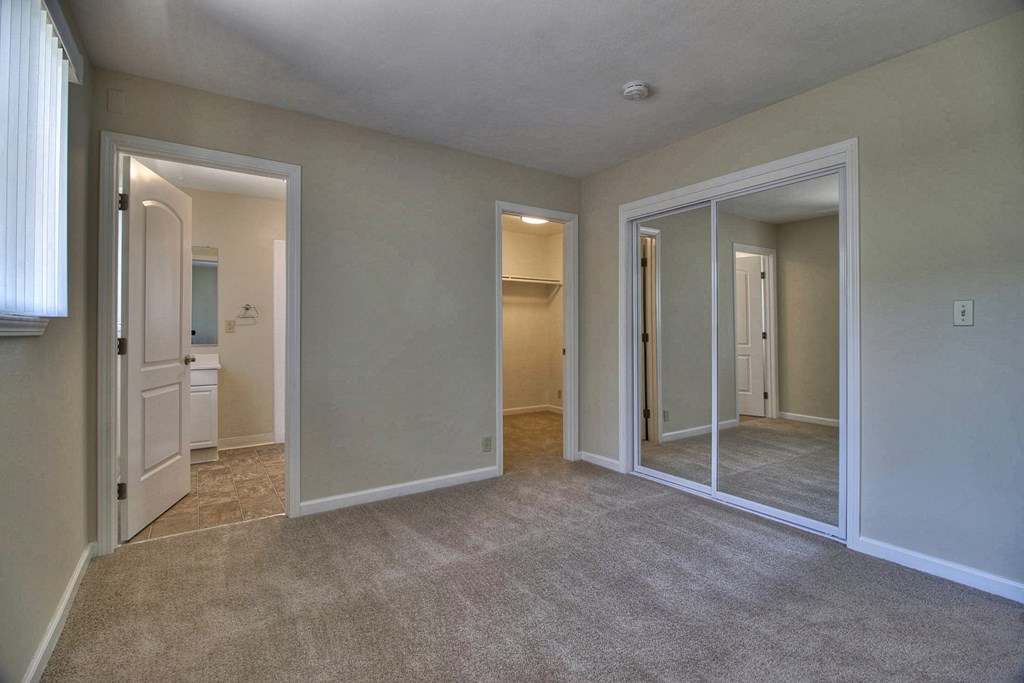 a bedroom with mirrors and carpeting in an empty house