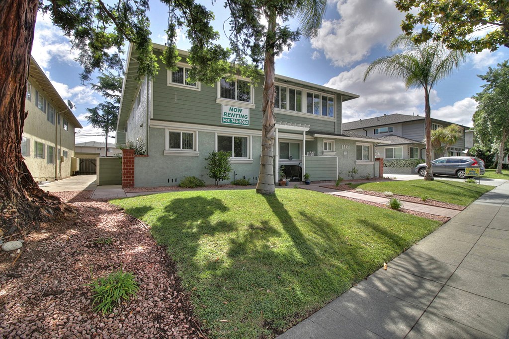 a green house with a lawn and trees in front of it