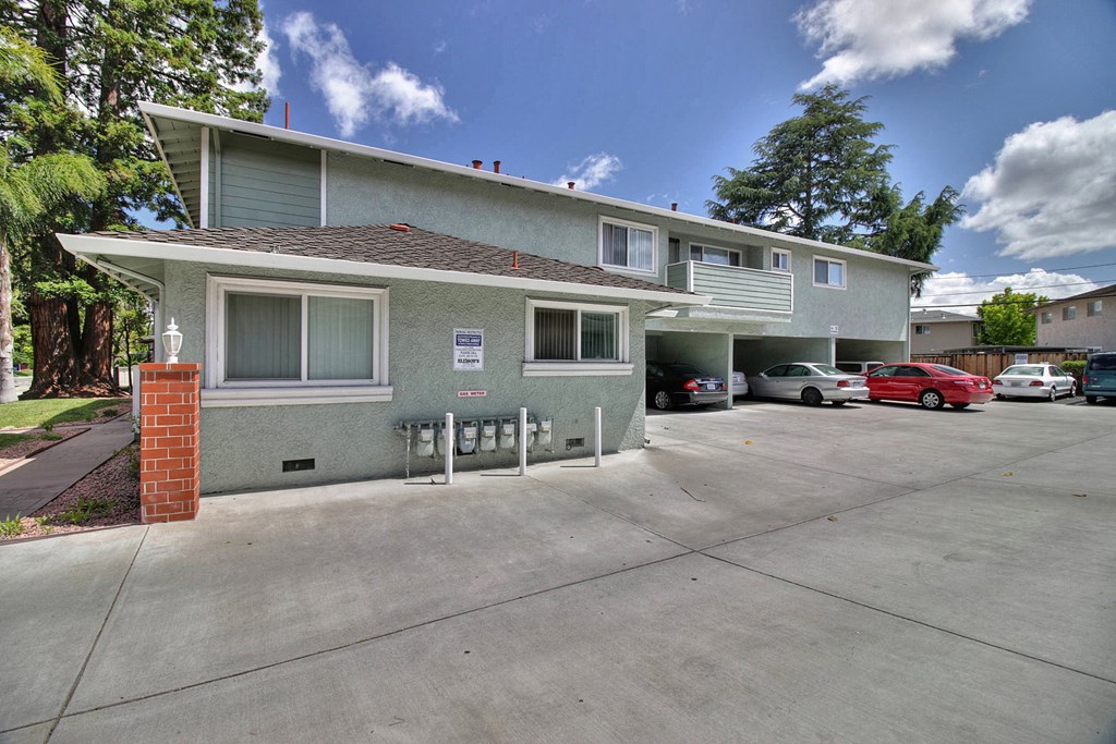 a gray house with a parking lot and cars in front of it