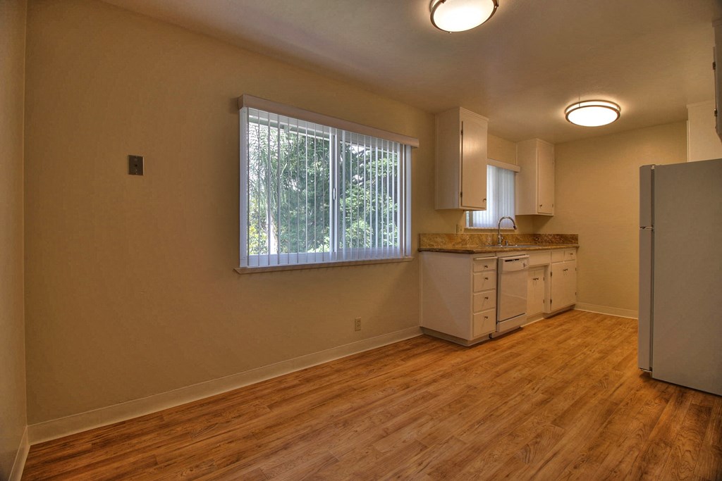an empty kitchen with a refrigerator and a window