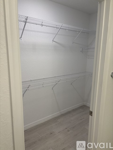 A white closet with clothes hangers and a door.
