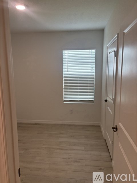 A room with a wooden floor and a window with blinds.