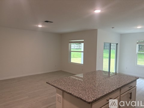 A spacious room with a granite countertop and a window overlooking a green area.