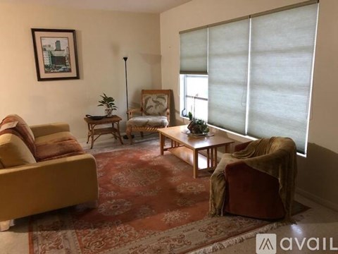 A living room with a sofa, armchair, and a table with a plant on it.