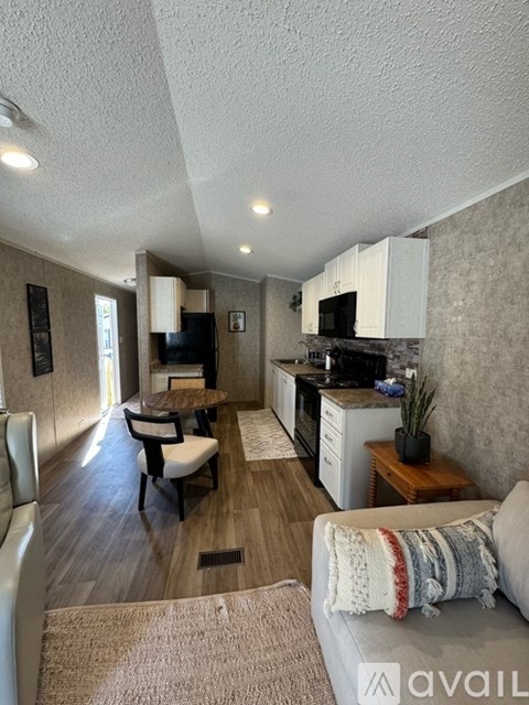 A living room with a couch and a kitchen area in the background.