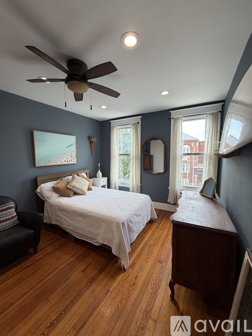 A bedroom with a bed, chair, and a ceiling fan.