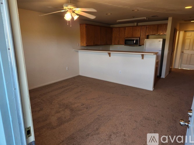 A room with a fan, a microwave, and a refrigerator.