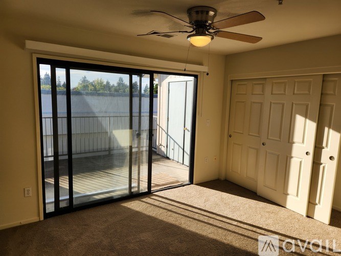 A room with a ceiling fan and a sliding glass door leading to a deck.