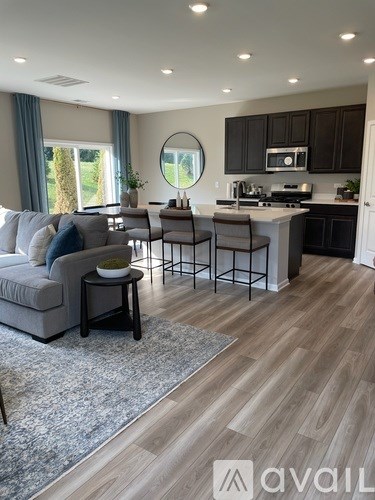 A modern kitchen and living room with a grey sofa and wooden floors.
