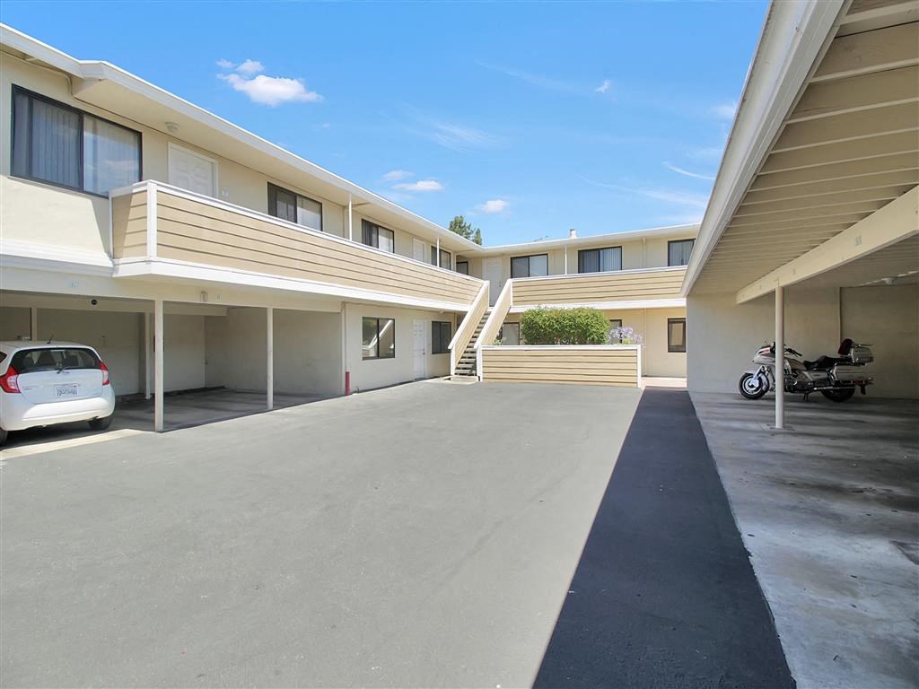 a parking lot in front of a building with cars and a motorcycle