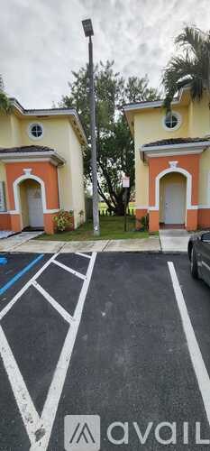 A parking lot with a car parked and two buildings in the background.