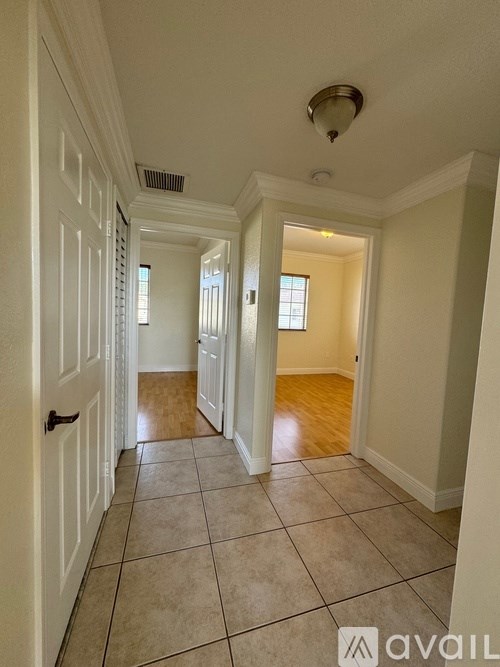 A hallway with white walls and a tiled floor.
