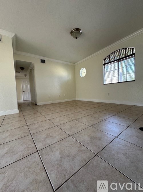 A room with tiled flooring and a window with blinds.