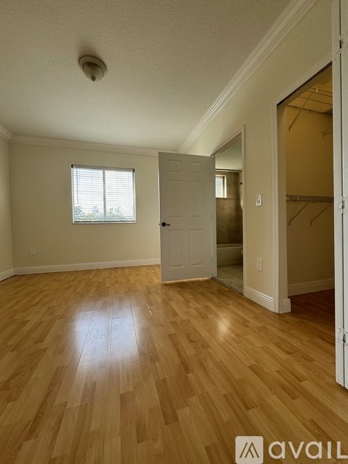 A room with wooden flooring and a window with blinds.