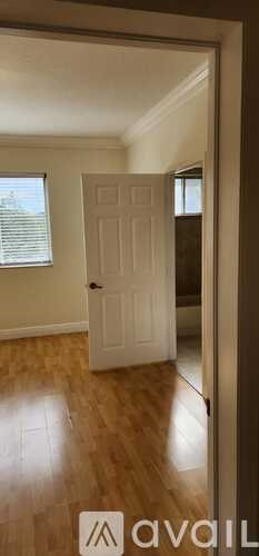 A white door is in the middle of a room with wooden floors.