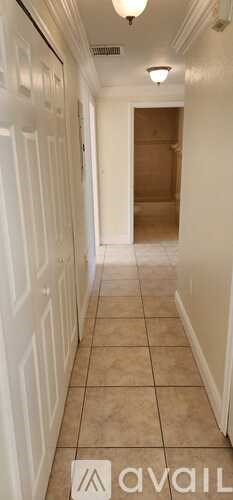 A hallway with white doors and beige tiled flooring.