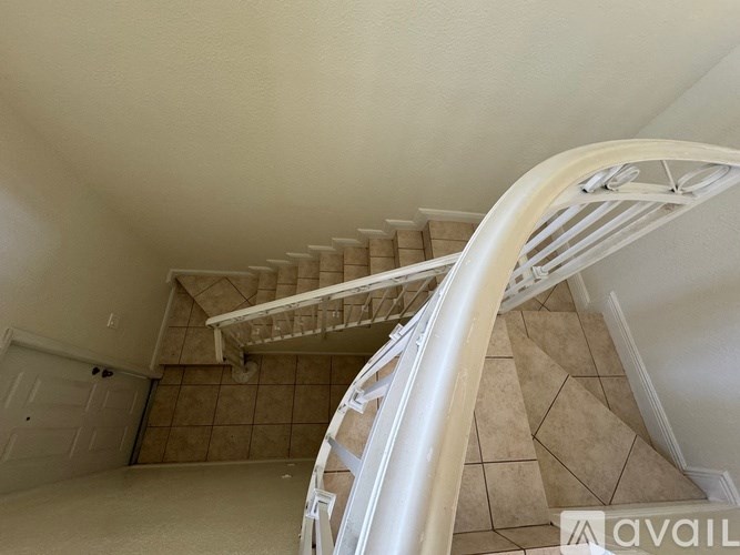 A staircase with a white railing and beige tiles.