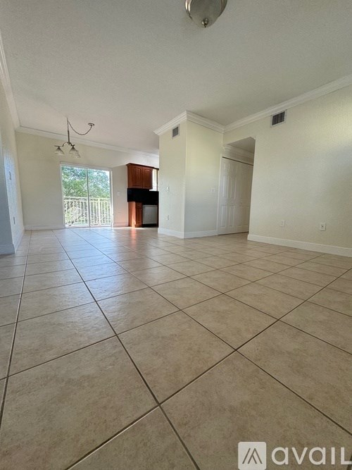 A spacious living room with tiled flooring and a large window.