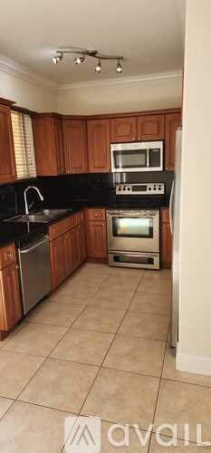 A kitchen with wooden cabinets and black countertops.