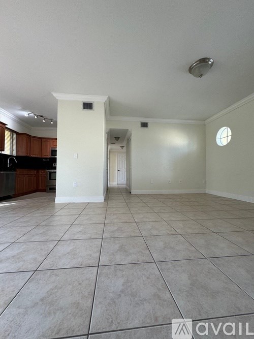 A spacious living room with a kitchen in the background.