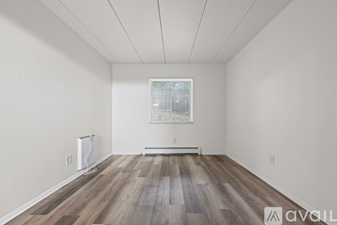 A room with wooden flooring and a window with blinds.