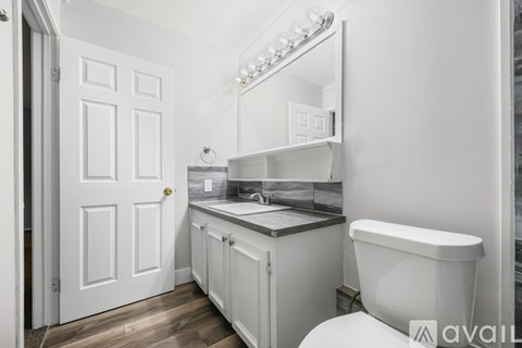 A bathroom with a white toilet, sink, and cabinet.