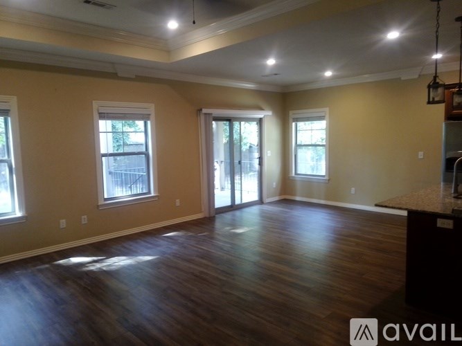 A spacious room with wooden floors and a large window.