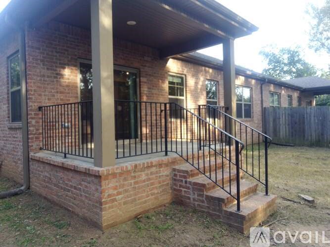A house with a black iron railing and a brick base.