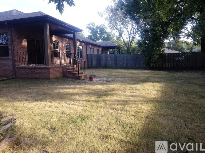 A backyard with a house, fence, and trees.