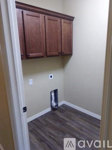 A room with brown cabinets and a trash can.
