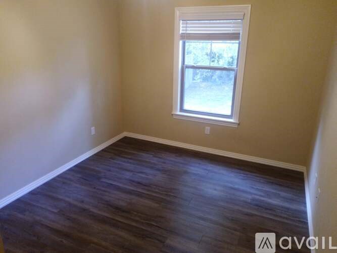 A room with a window and wooden flooring.