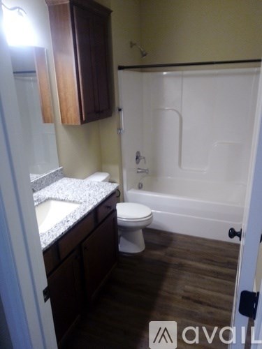 A bathroom with a toilet, sink, and wooden cabinets.