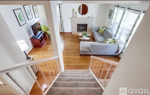 A living room with a grey couch and a fireplace with a mirror above it.