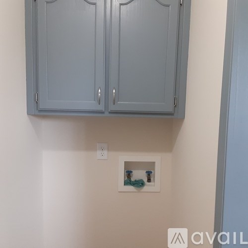 A wall with a small shelf and two cabinets above it.