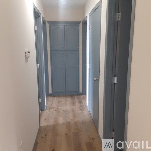 A hallway with a blue door and a white wall.